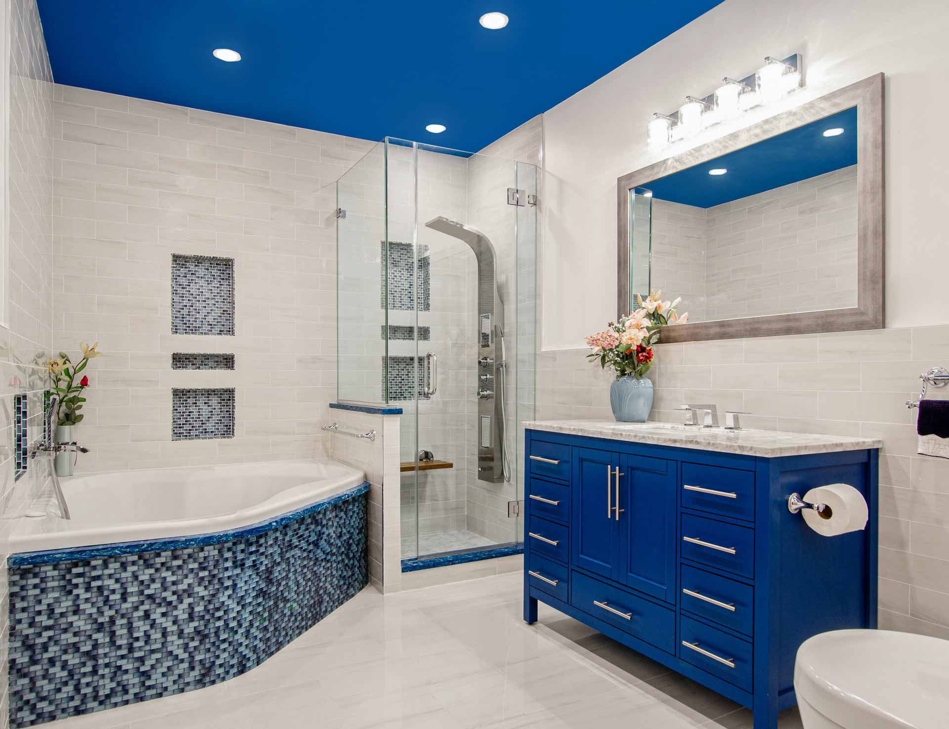 Renovated blue and white bathroom. Blue ceiling. Blue vanity. Blue tile. Jacuzzi tub. White tiles. Stand up shower.