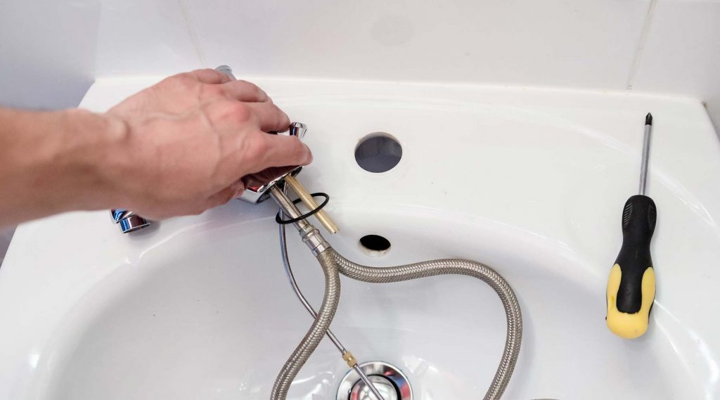 Plumber installing a new faucet in a sink