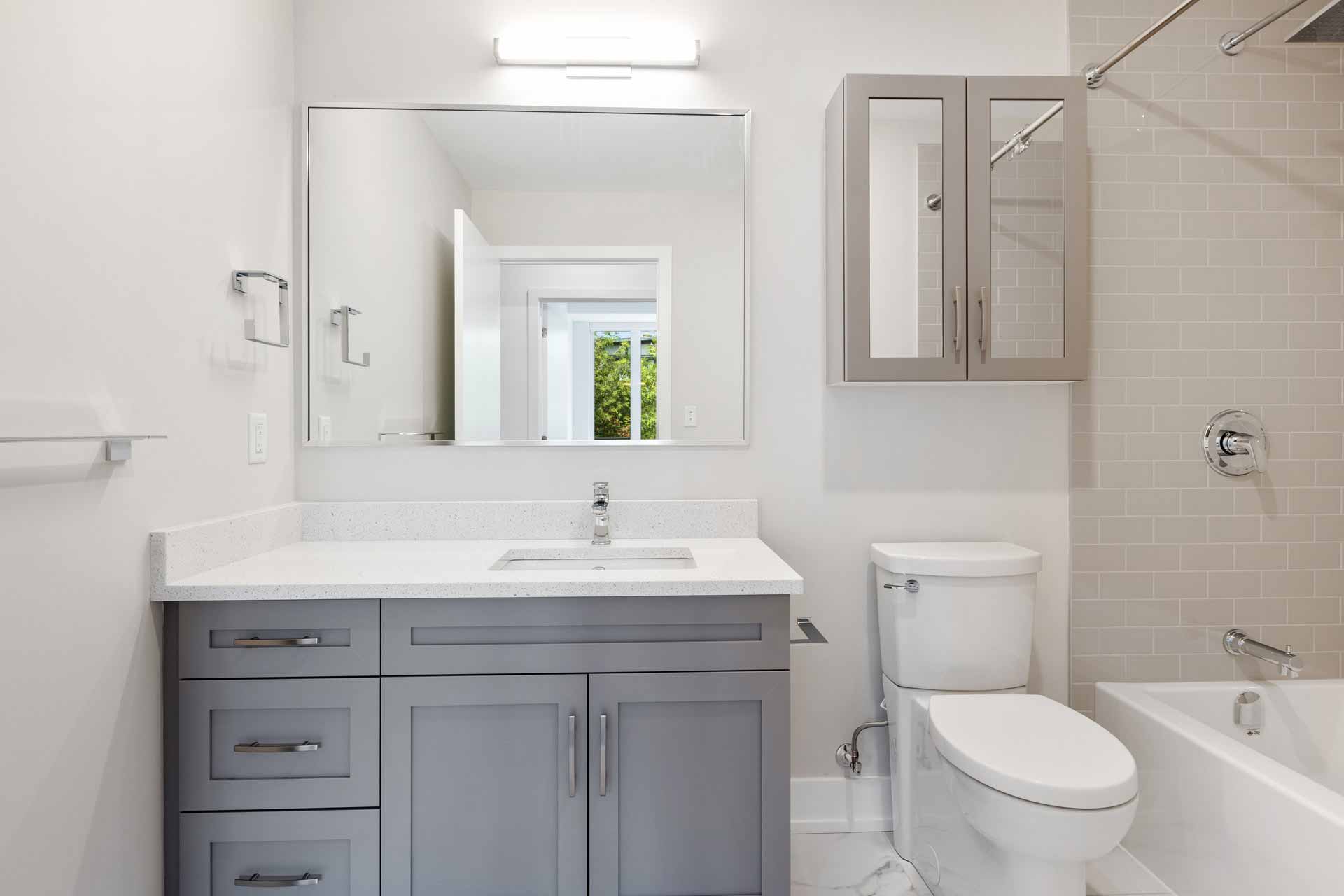 A clean, bright bathroom with light grey tiles